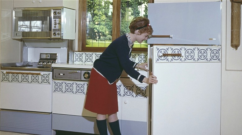 A woman opening a refrigerator with matching kitchen appliances