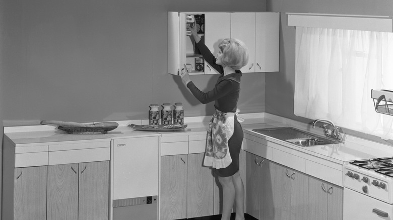 A woman in a model kitchen with white and woodgrain cabinets