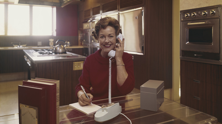 A woman on the phone in a wood grain kitchen