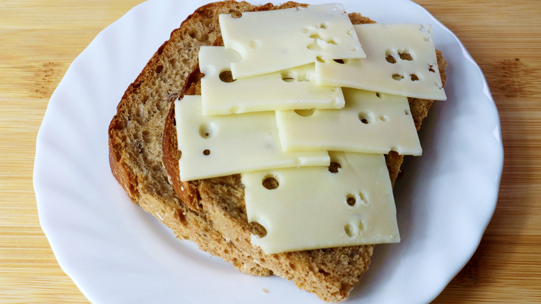 Two pieces of toast with sliced Swiss cheese on top on a plate