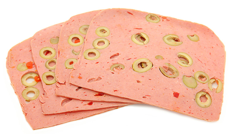 Slices of olive loaf lunch meat on a white background
