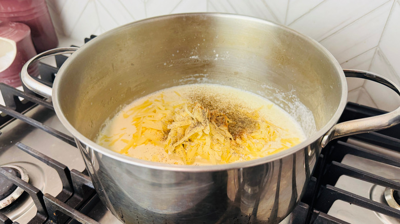 Creamy sauce, shredded cheddar cheese, and seasonings in pot