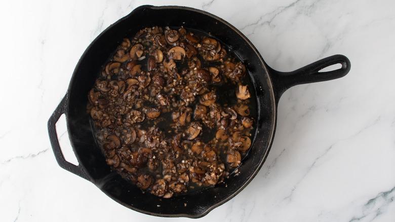 Sauteed mushrooms in a large skillet with liqueur