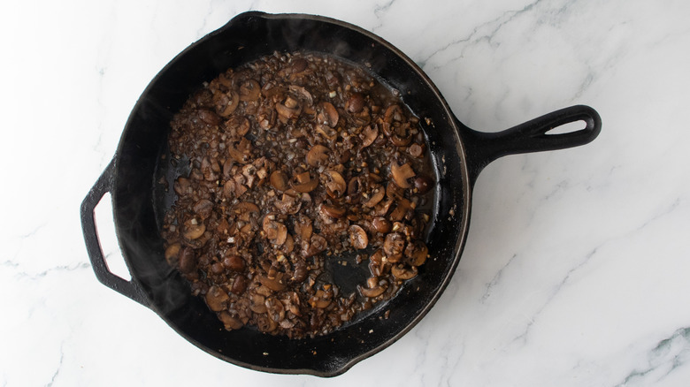Sauteed mushrooms in a large skillet with reduced liqueur