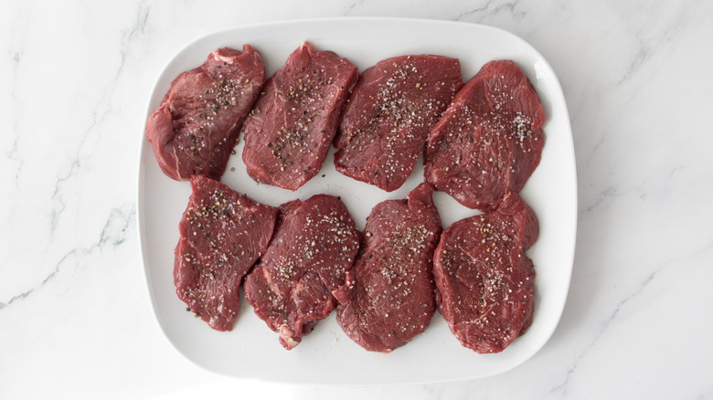 Filet mignon steaks on a platter seasoned with salt and pepper