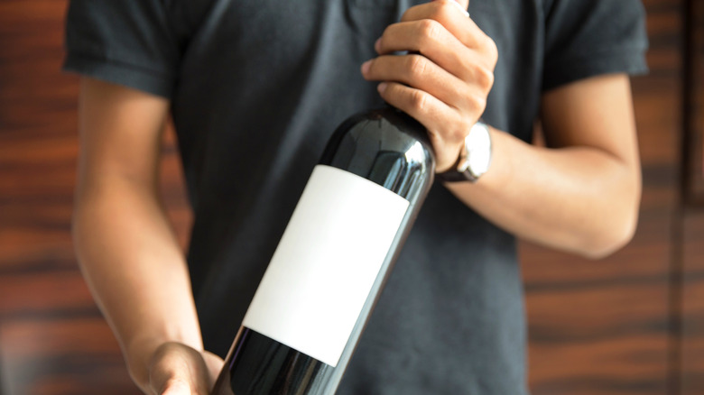 A man carrying a bottle of wine