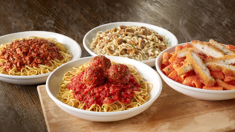 Four different pastas from Olive Garden on a wooden table