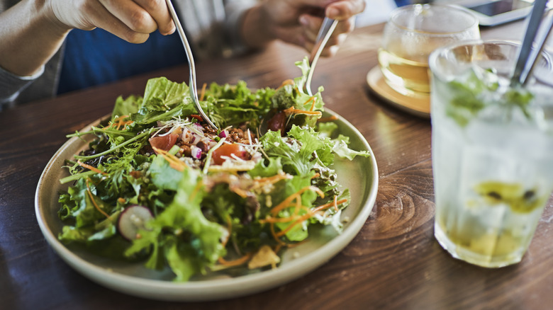 closeup of a salad plate and someone digging in with a fork