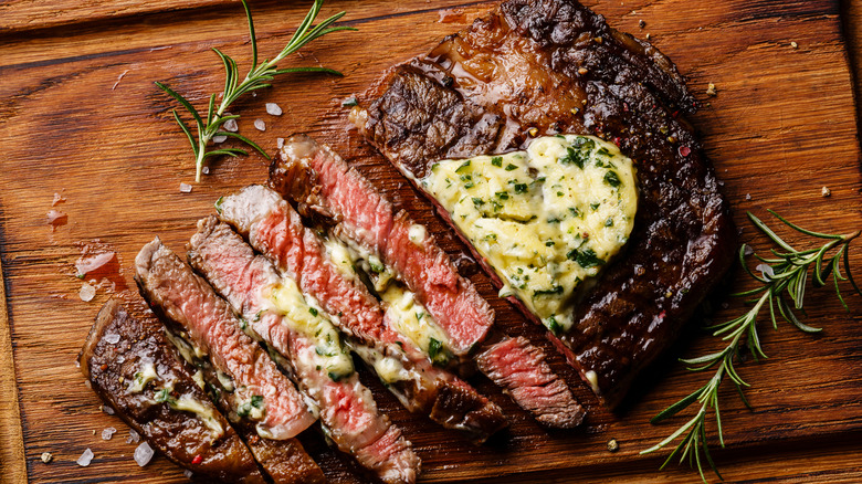 Sliced steak with a nice, crispy exterior, served on a wooden tray