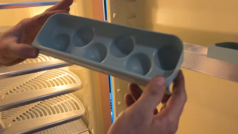 hands holding a vintage blue egg bin from a 1954 GE refrigerator