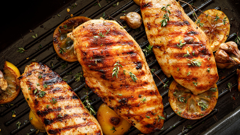 Grilled chicken is cooking with herbs and lemon slices