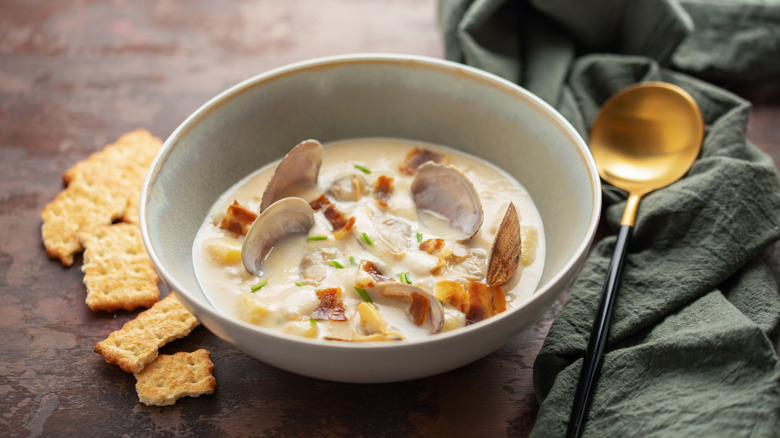 Clam chowder in a bowl with crackers on the side.