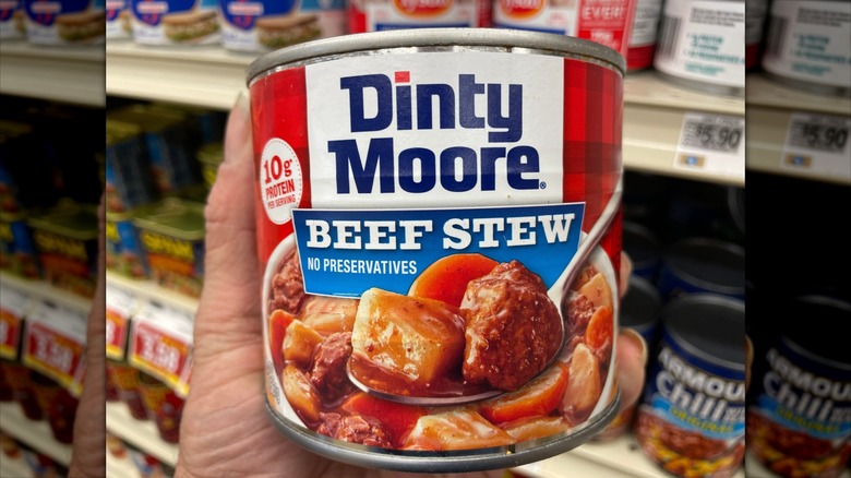 Someone holds a can of Dinty Moore beef stew at the supermarket.