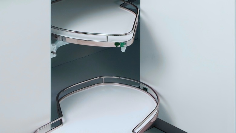 A white super lazy Susan with a sleek pull-out mechanism, installed in a corner kitchen cabinet.