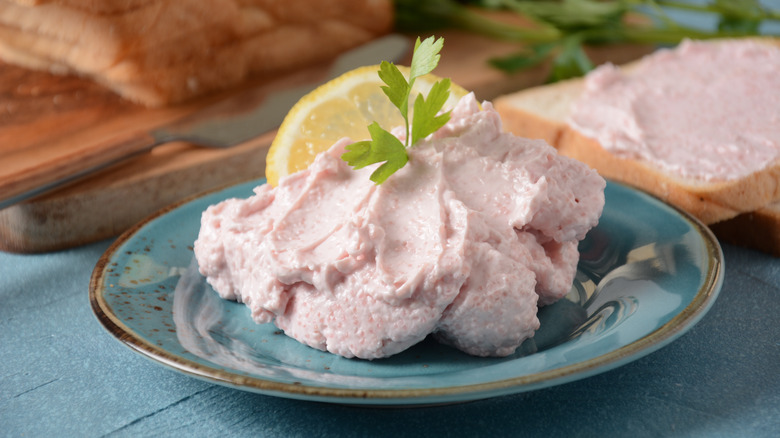 A blue plate holding shrimp mousse garnished with parsley and a slice of lemon