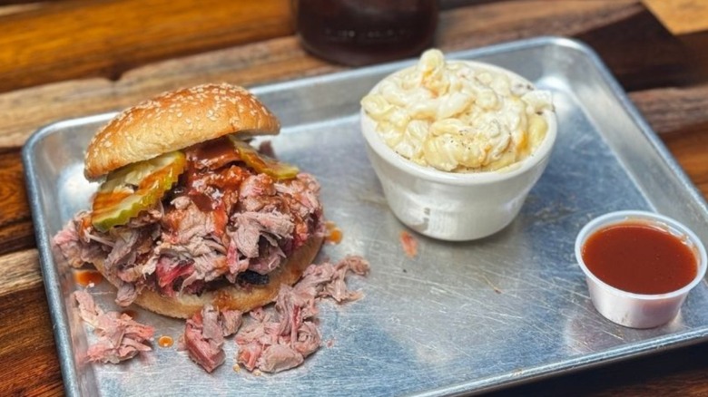 Barbecue pork sandwich and sides on a silver tray.
