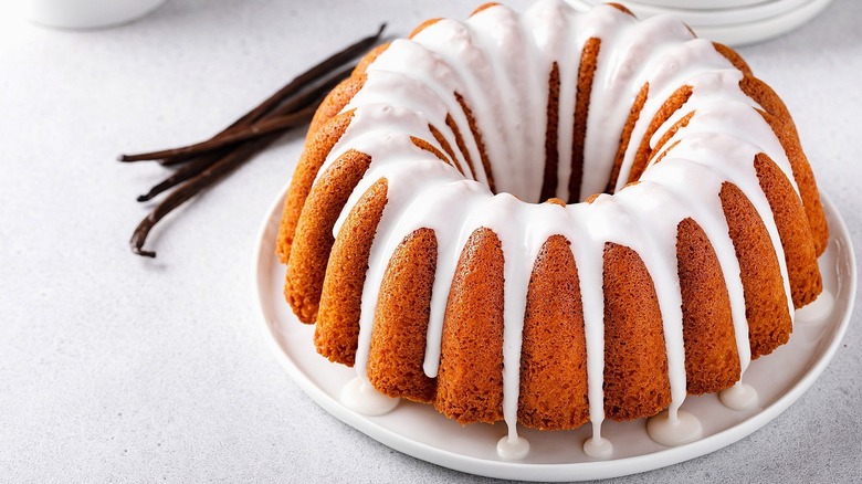 Whole bundt cake topped with a vanilla glaze on a white plate