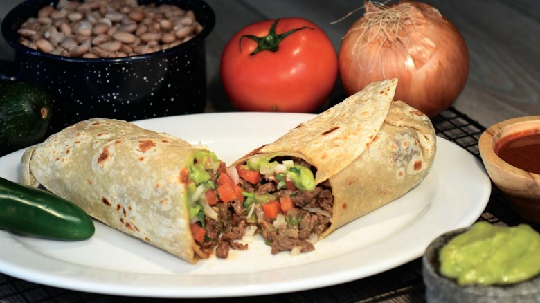 Carne asada burrito from Roberto's Taco Shop cut in half on a white plate