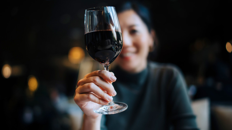 Glass of red wine held by woman