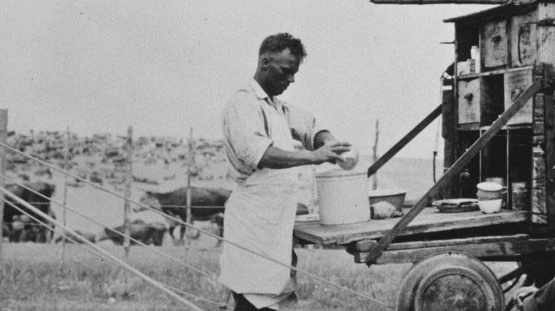 A cowboy cleaning dishes on a wagon