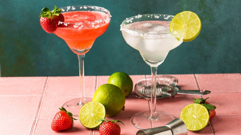 A glass of strawberry margarita and a glass of traditional margarita