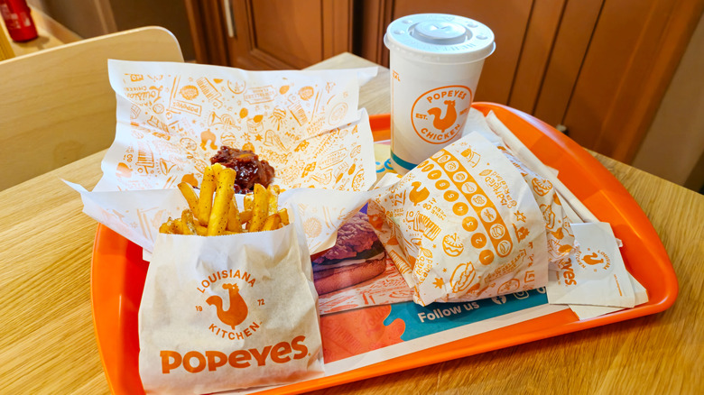 Popeyes fried chicken sandwich with fries and a drink on a tray