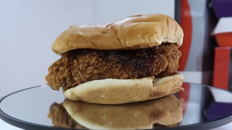 Popeyes Honey BBQ Chicken Sandwich on a rotating mirrored platform