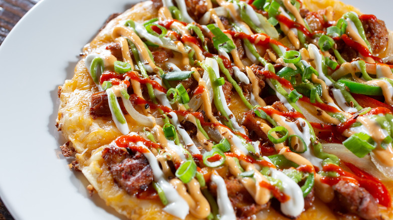 Close up of a pizza doused with toppings and sauces