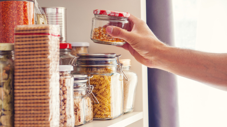 a hand grabbing a container out of a pantry