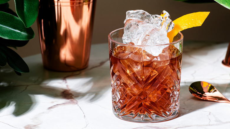 A bourbon cocktail with a lemon peel garnish.