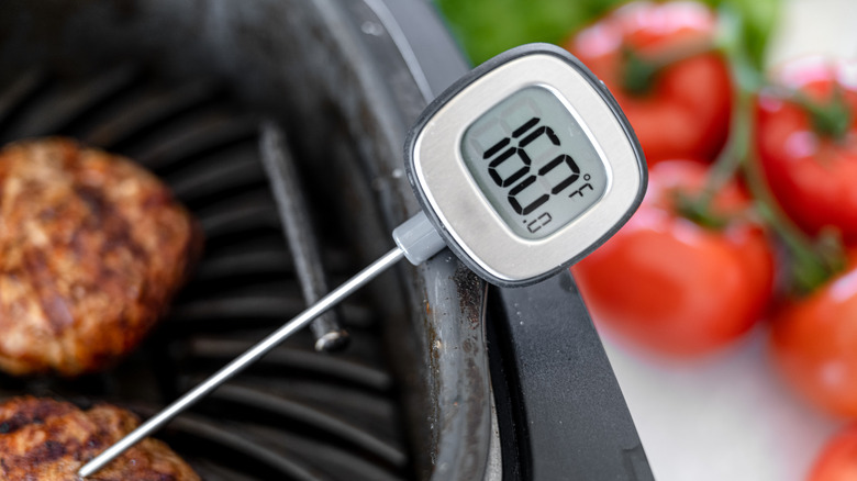 Meat thermometer in ground beef burgers.