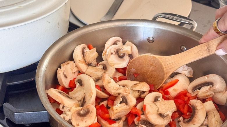 hand stirring mushrooms and peppers
