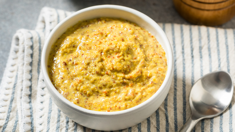 grainy dijon mustard in a white bowl with a spoon