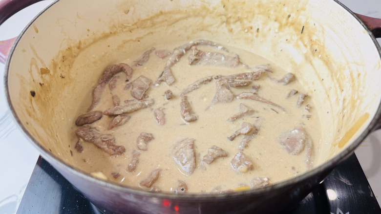 Beef stroganoff sauce and steak strips in Dutch oven