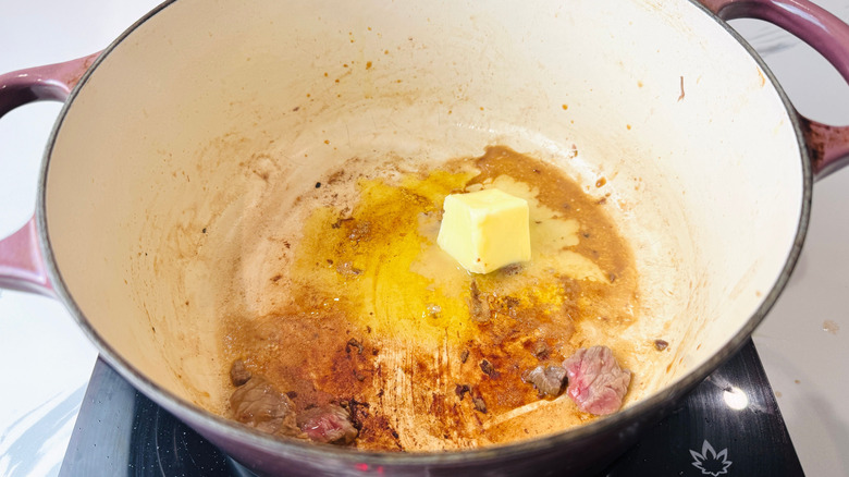 Butter and oil with beef remnants in Dutch oven