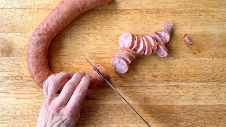 Slicing andouille sausage on cutting board