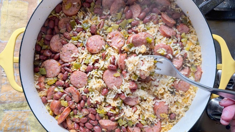 Fluffing one-pot red beans and rice in yellow pot with fork