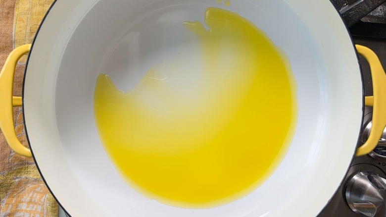 Olive oil heating in large yellow pot on stovetop