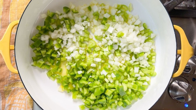 Chopped onion, green bell pepper, and celery in large yellow pot on stovetop
