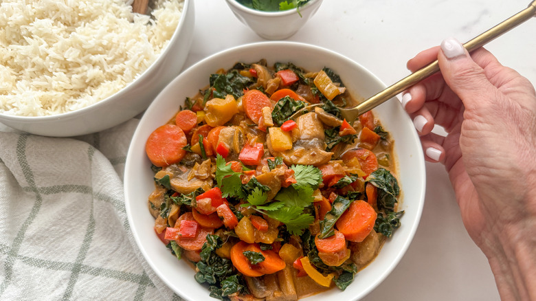 hand with spoon in curry bowl