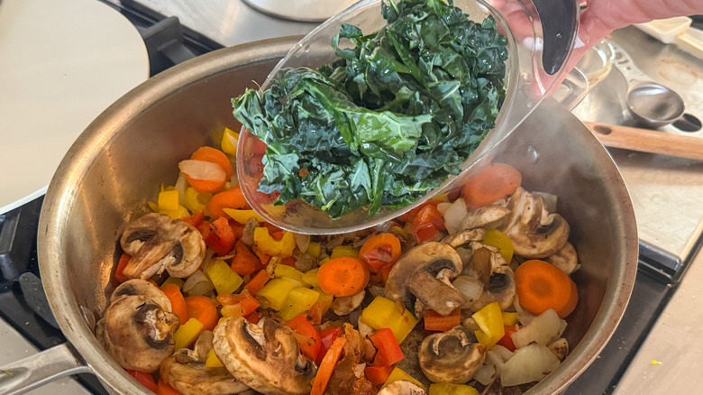 hand adding kale to pan