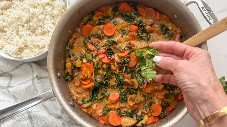 hand adding cilantro to curry