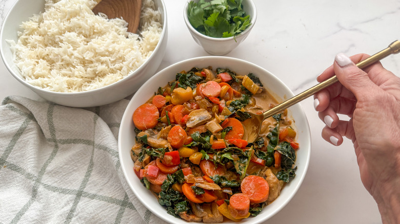 hand with spoon in bowl of curry