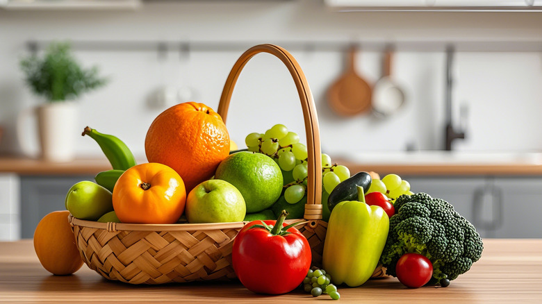 Fruits and veggies are arranged in and around a basket on a kitchen counter.