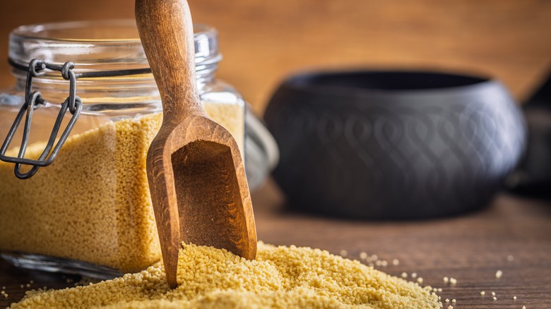A jar of couscous with a wooden scoop