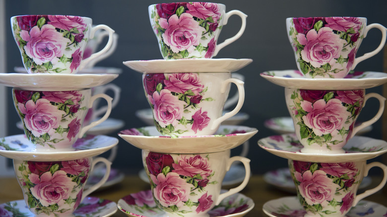 Several stacks of pretty, floral-print teacups on saucers.