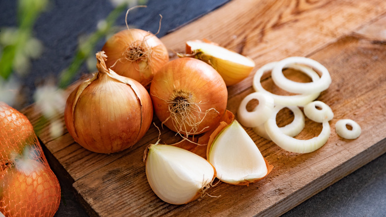 Yellow onions are arranged on a cutting board.