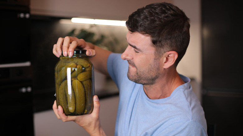Person struggling to open a pickle jar