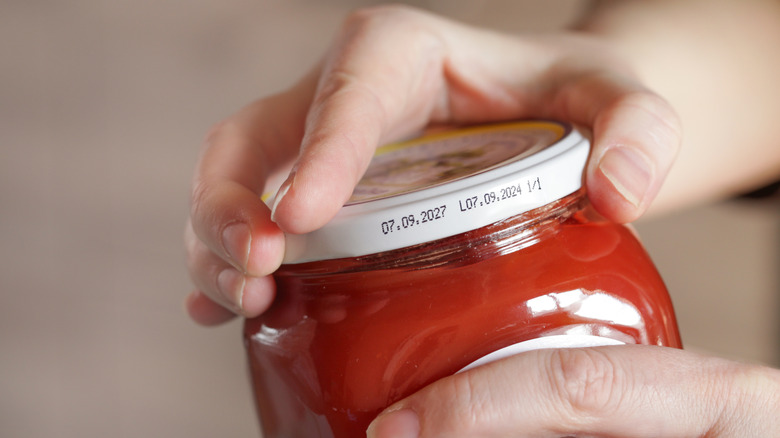 Person trying to open a jar of preserves
