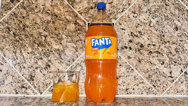 Two-liter and glass of Fanta Orange Soda on marble counter